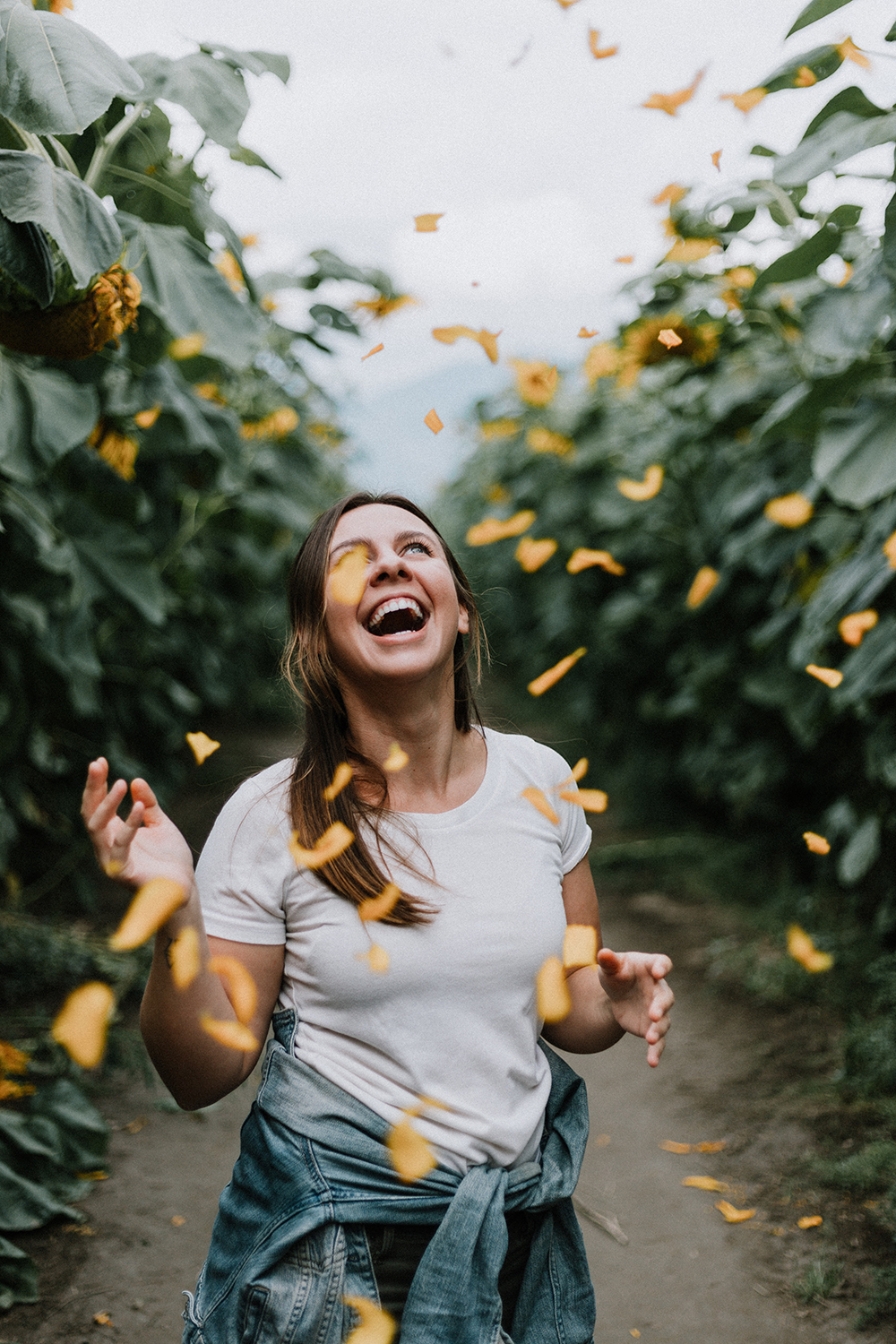 femme qui rit au milieu de pétales de fleurs jaunes